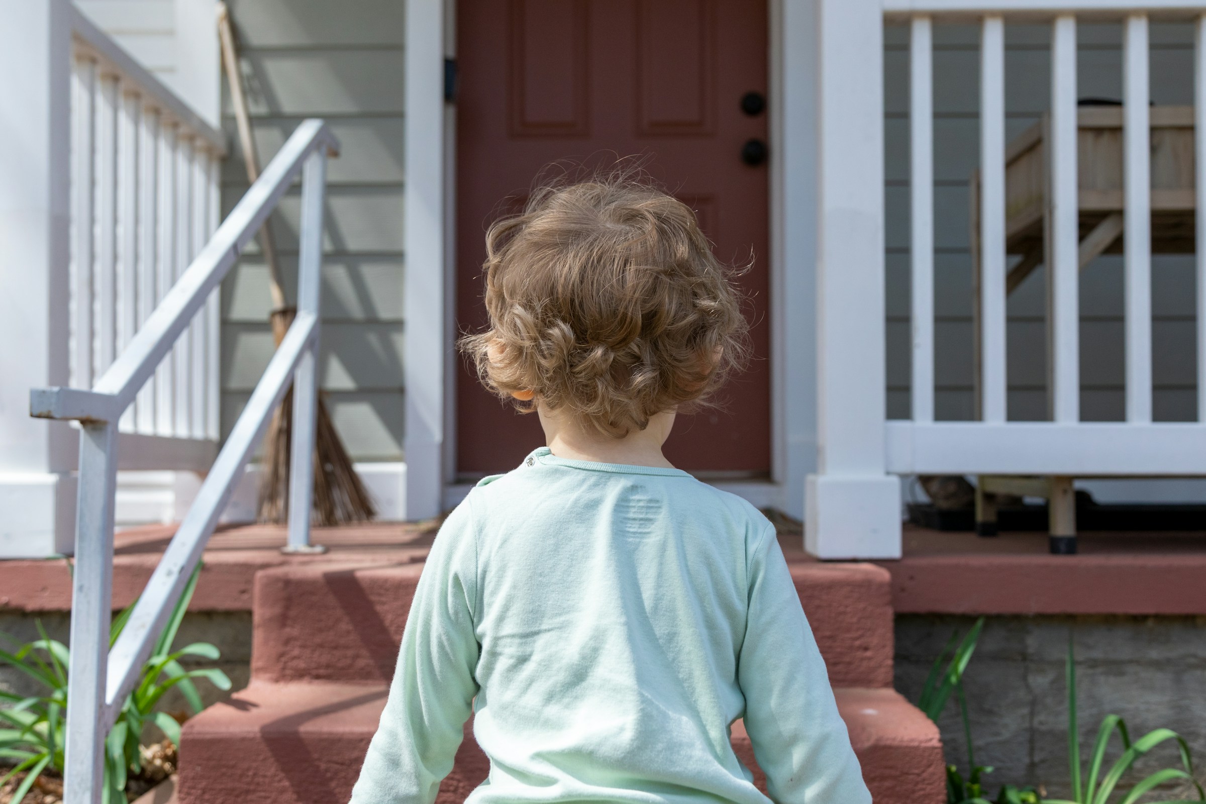 A child walking up the front steps of a family home